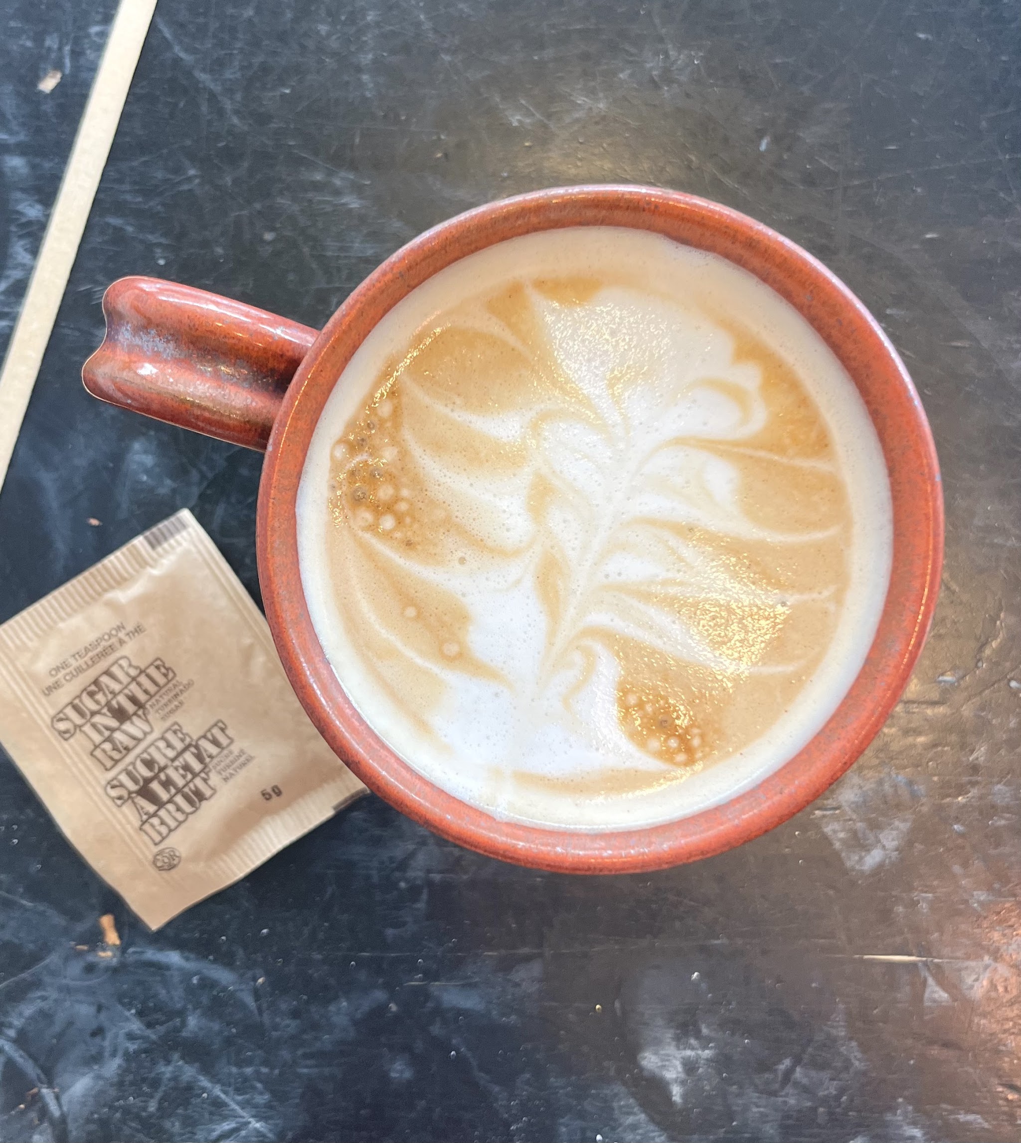 Latte art in a handmade red ceramic mug